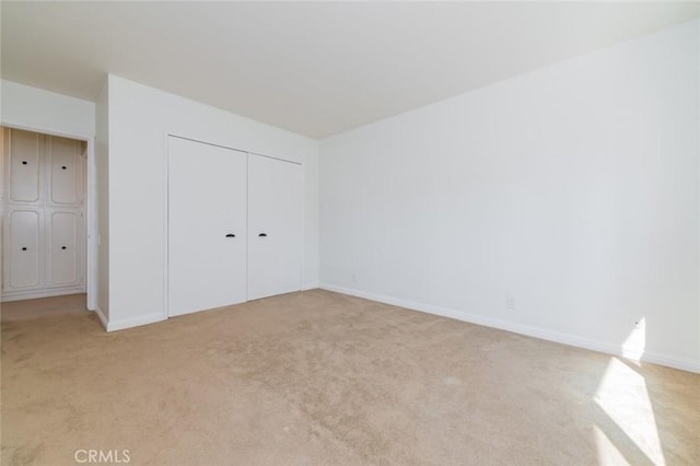 unfurnished bedroom with light carpet and a closet