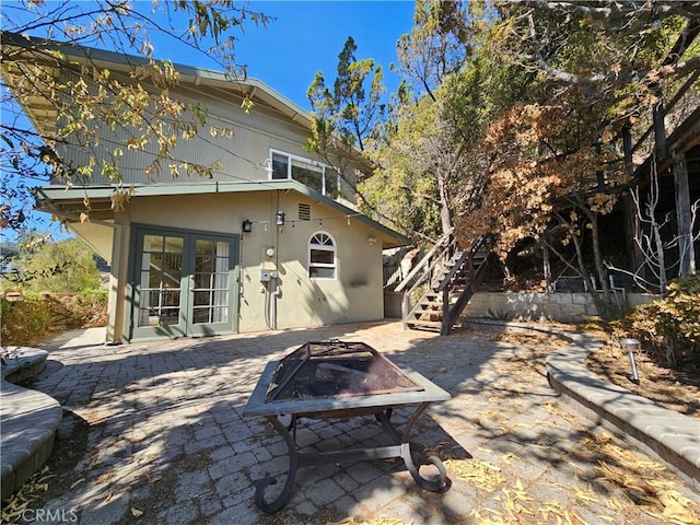 rear view of property with french doors, a patio, and a fire pit