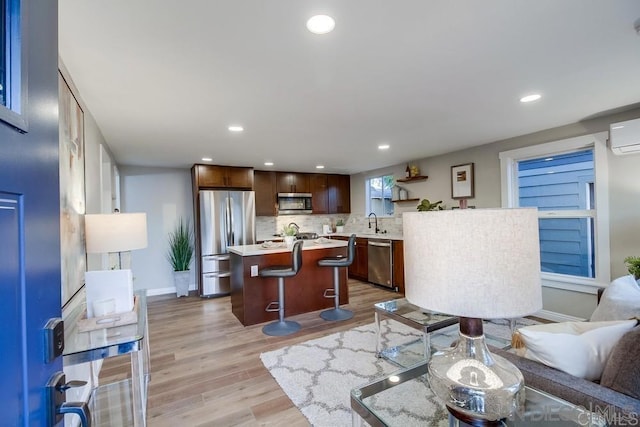 living room with an AC wall unit, sink, and light wood-type flooring