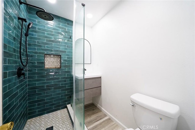 bathroom with vanity, toilet, wood-type flooring, and a tile shower