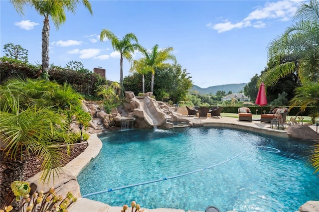 view of swimming pool with a patio area, a mountain view, and a water slide