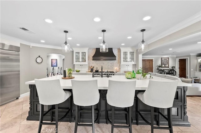 kitchen with decorative light fixtures, built in fridge, custom range hood, and a large island