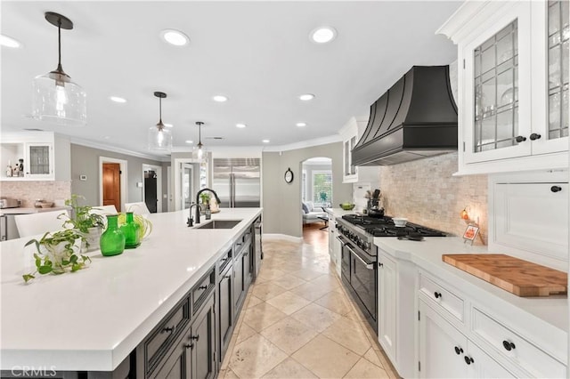 kitchen featuring high end appliances, custom range hood, white cabinets, and hanging light fixtures