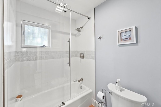 bathroom with toilet and bath / shower combo with glass door