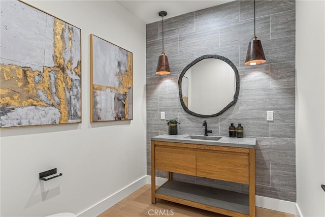 bathroom with hardwood / wood-style floors, vanity, and tile walls