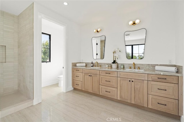 bathroom with a tile shower, vanity, and toilet