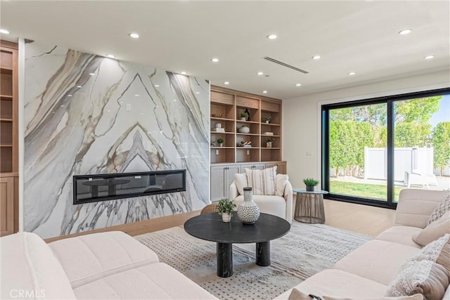 living room featuring a high end fireplace and light hardwood / wood-style floors