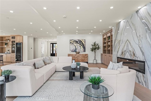 living room with a high end fireplace and light wood-type flooring