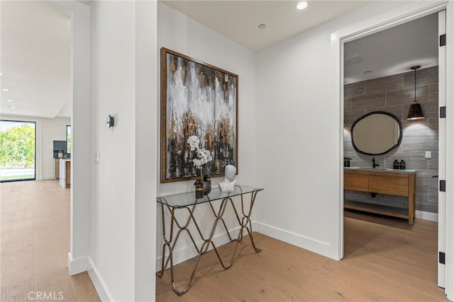 hall featuring hardwood / wood-style flooring, sink, and tile walls