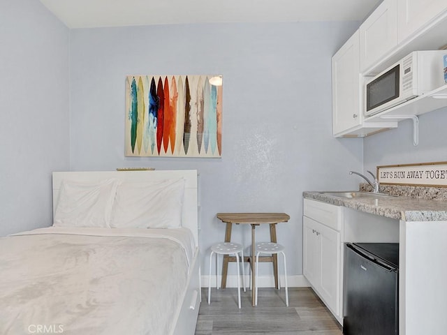 interior space with stainless steel refrigerator, hardwood / wood-style flooring, and sink