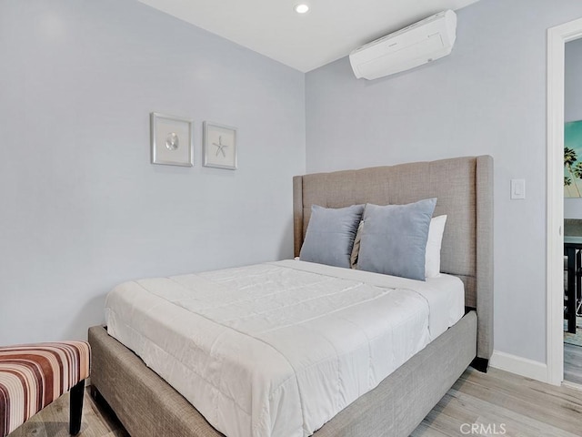 bedroom featuring light hardwood / wood-style flooring and a wall unit AC