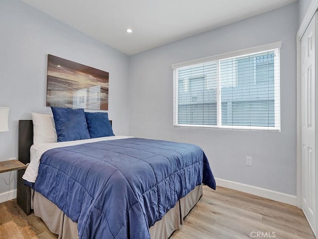 bedroom featuring multiple windows, light hardwood / wood-style flooring, and a closet