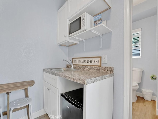 kitchen featuring light hardwood / wood-style floors, white cabinetry, and sink