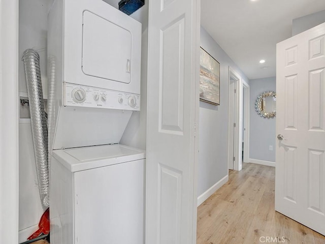 laundry area with stacked washer / dryer and light hardwood / wood-style flooring