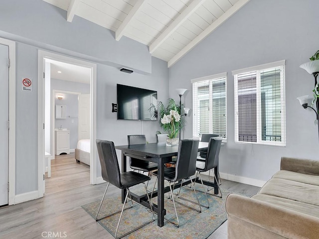 dining area featuring light hardwood / wood-style floors and vaulted ceiling with beams