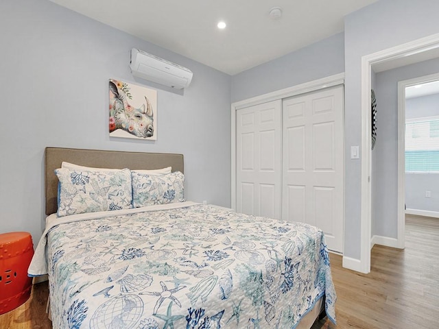 bedroom with hardwood / wood-style floors, a closet, and a wall mounted air conditioner