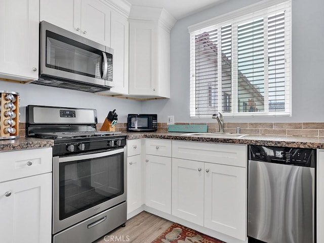 kitchen featuring sink, white cabinets, stainless steel appliances, and light hardwood / wood-style flooring