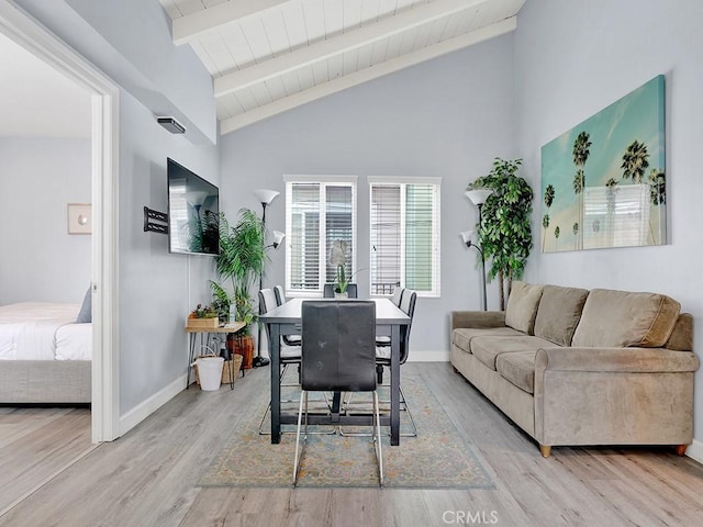 dining area with light wood-type flooring and lofted ceiling with beams