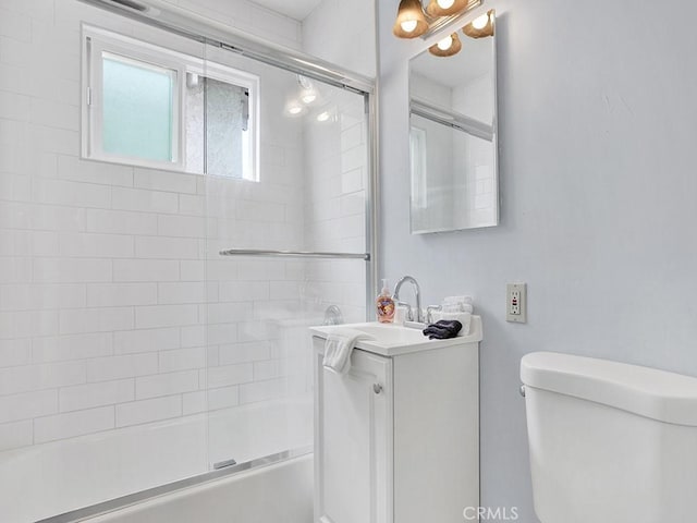 full bathroom featuring toilet, shower / bath combination with glass door, and vanity