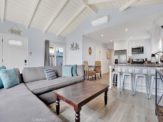 living room with vaulted ceiling with beams and light hardwood / wood-style flooring