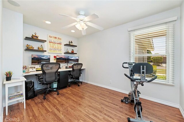 home office with light hardwood / wood-style floors and ceiling fan