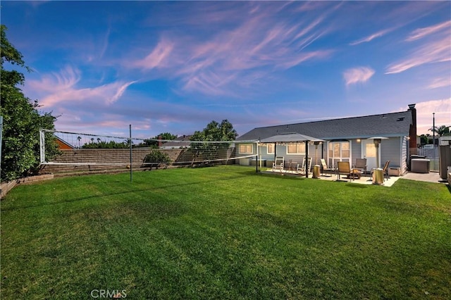 yard at dusk with central air condition unit, a gazebo, and a patio area