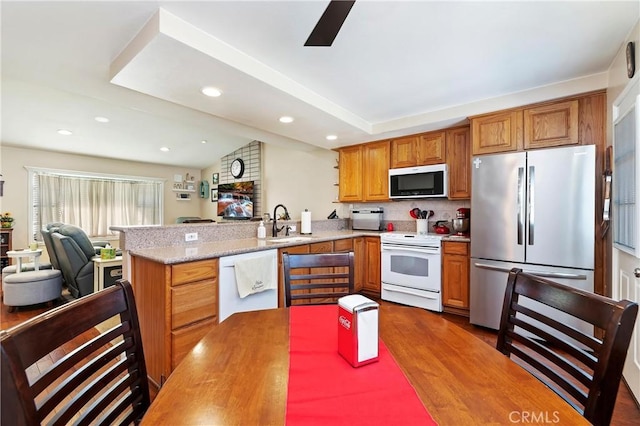 kitchen with kitchen peninsula, dark hardwood / wood-style flooring, sink, lofted ceiling, and stainless steel appliances