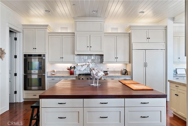 kitchen with dark hardwood / wood-style floors, a kitchen island, butcher block counters, and appliances with stainless steel finishes