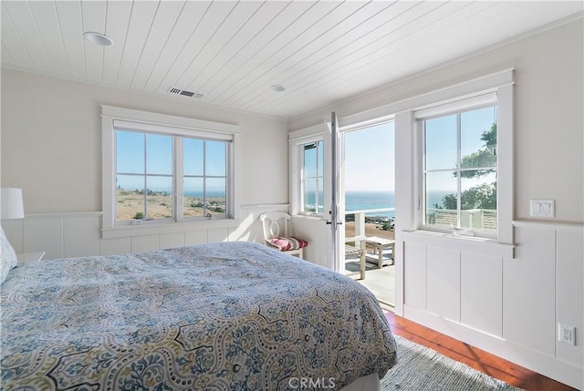 bedroom featuring hardwood / wood-style floors, a water view, and wooden ceiling