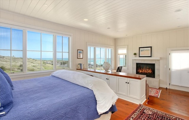 bedroom featuring a tiled fireplace, wooden ceiling, and wood finished floors