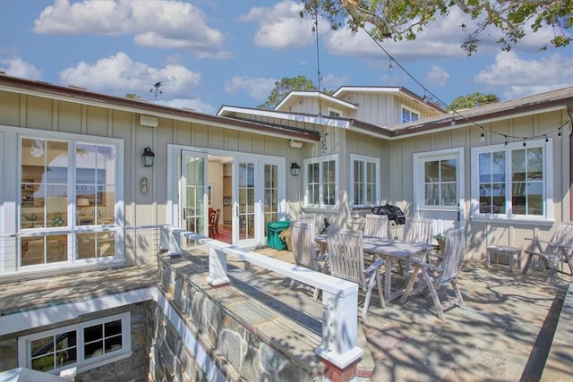 rear view of property with outdoor dining area and board and batten siding