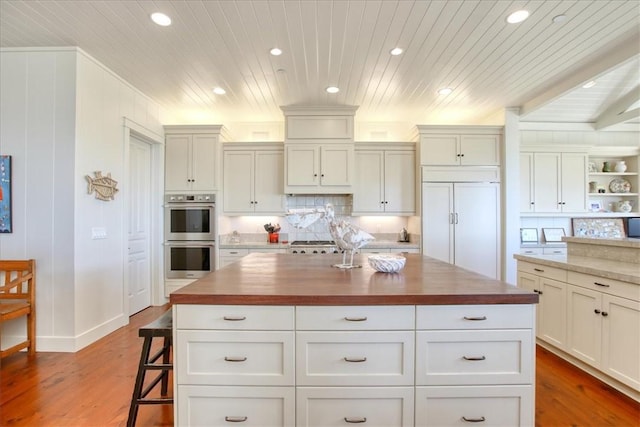 kitchen with wood counters, paneled built in fridge, double oven, and wooden ceiling