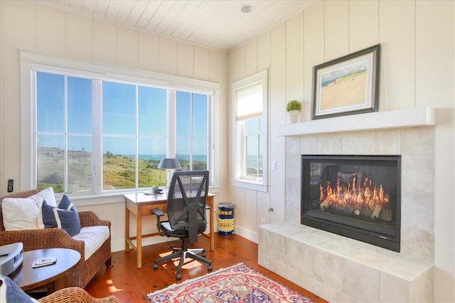office space with wood finished floors, a tiled fireplace, and baseboards