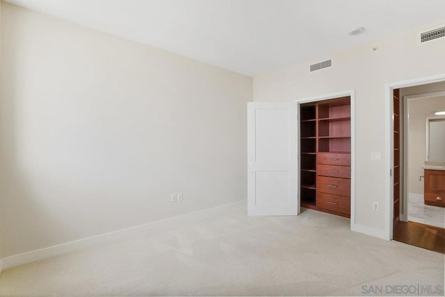 unfurnished bedroom with a walk in closet, light colored carpet, and a closet