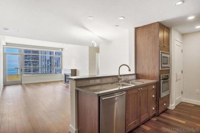 kitchen with kitchen peninsula, sink, dark hardwood / wood-style floors, and appliances with stainless steel finishes