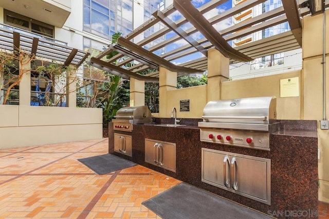 view of patio with a pergola, an outdoor kitchen, area for grilling, and sink