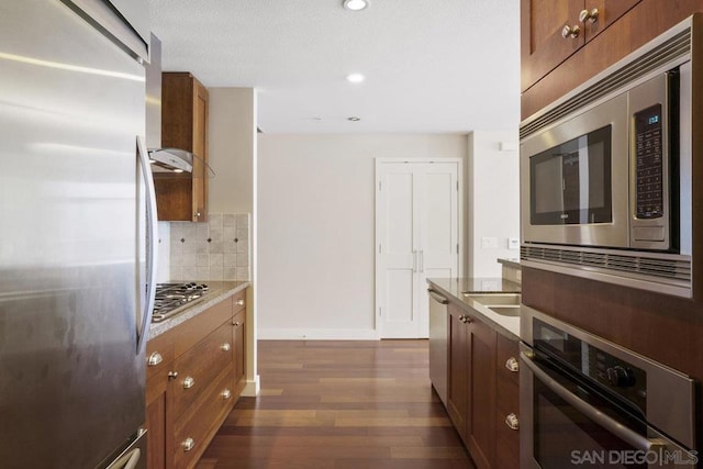 kitchen with backsplash, dark hardwood / wood-style floors, wall chimney exhaust hood, and stainless steel appliances