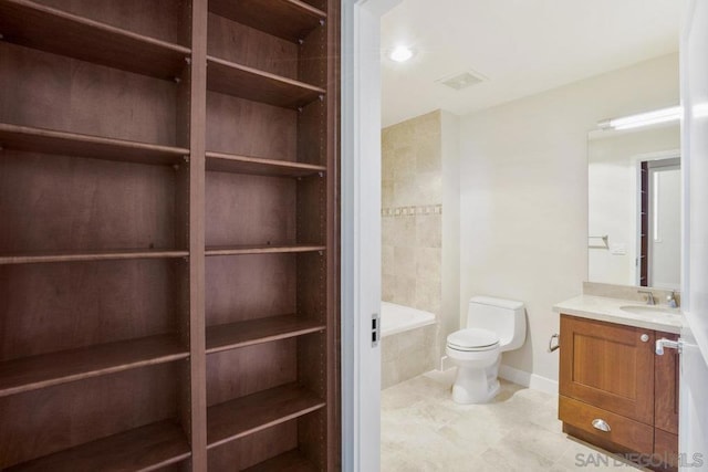 bathroom featuring vanity, toilet, and tiled tub