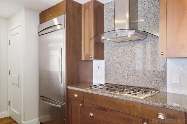 kitchen featuring backsplash, stainless steel appliances, and wall chimney range hood