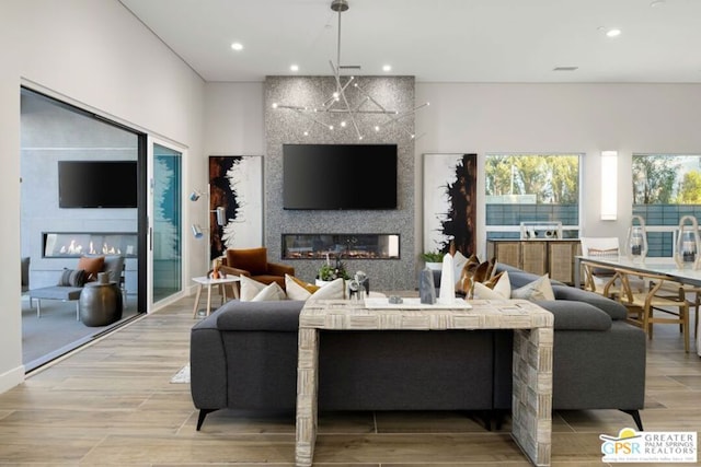 living room featuring light wood-type flooring, a large fireplace, and plenty of natural light