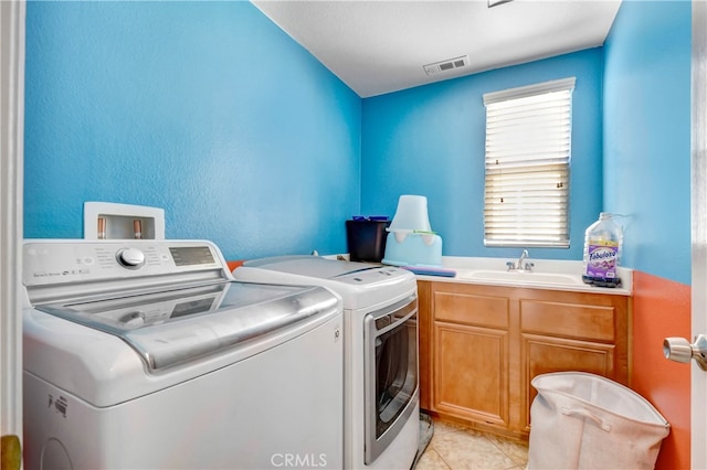 clothes washing area with cabinets, sink, independent washer and dryer, and light tile patterned flooring