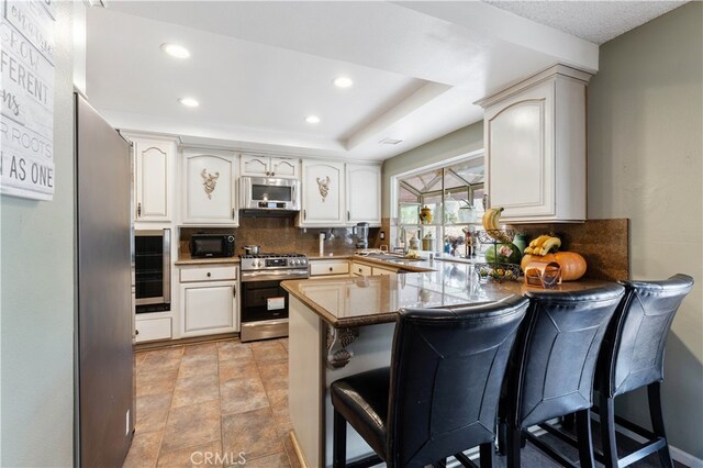 kitchen featuring a breakfast bar area, stainless steel appliances, kitchen peninsula, and tasteful backsplash