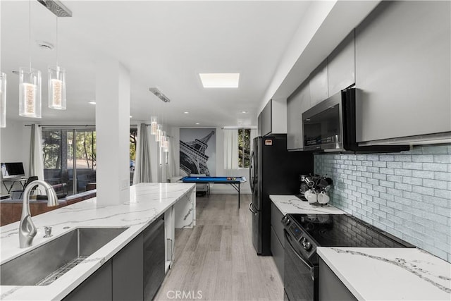 kitchen featuring pendant lighting, black appliances, sink, and light hardwood / wood-style flooring