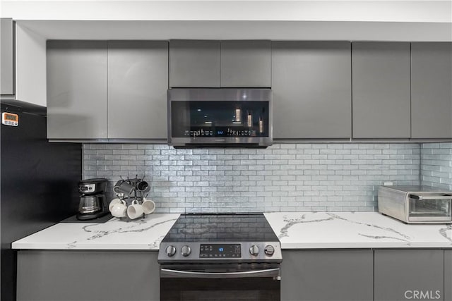 kitchen with light stone countertops, stainless steel appliances, and gray cabinets