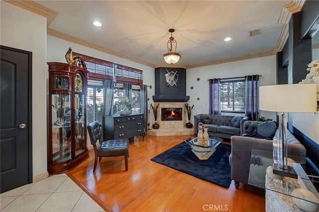 living room featuring hardwood / wood-style floors, ornamental molding, and a tiled fireplace