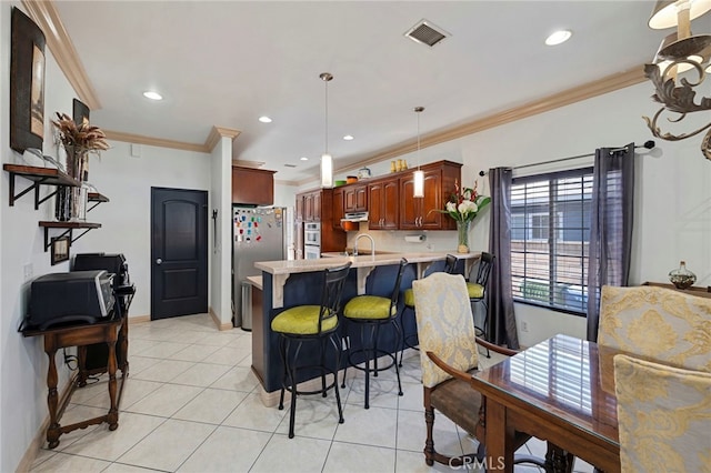 kitchen featuring kitchen peninsula, stainless steel fridge, crown molding, light tile patterned floors, and a breakfast bar area