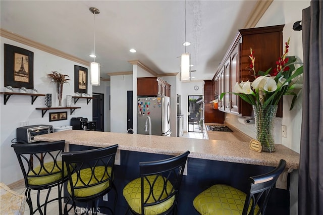 kitchen featuring kitchen peninsula, appliances with stainless steel finishes, a kitchen bar, ornamental molding, and hanging light fixtures