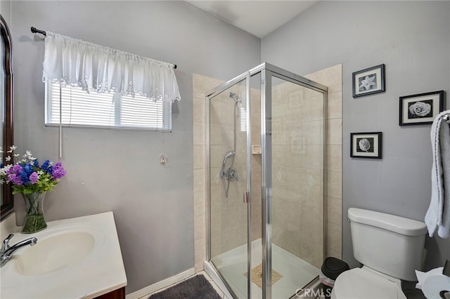 bathroom with vanity, toilet, and a shower with door