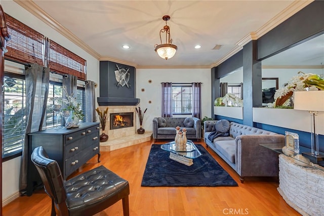 living room with a tiled fireplace, ornamental molding, and hardwood / wood-style flooring