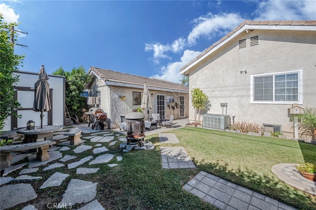 back of house with cooling unit, an outbuilding, a yard, and a patio